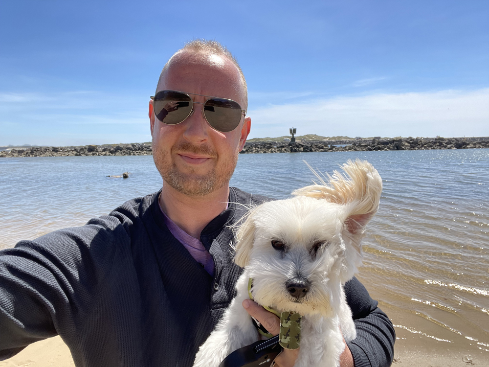 Meadow Outdoor Advertising Salesperson Joe McRae holding white dog by a river